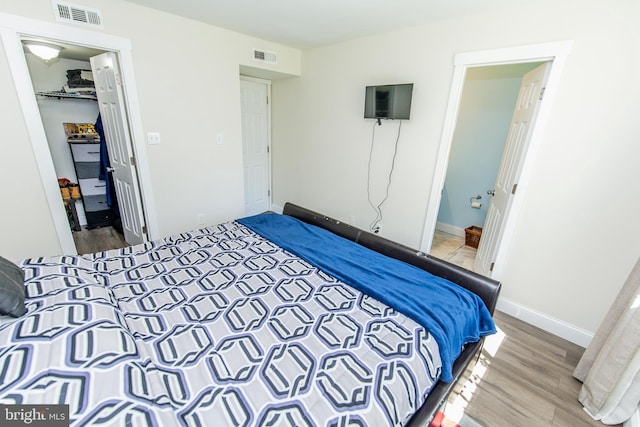 bedroom featuring wood finished floors, a closet, a spacious closet, and visible vents