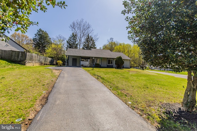 ranch-style home featuring aphalt driveway, fence, a front lawn, and an attached carport