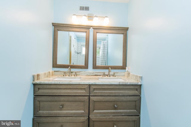 bathroom with double vanity, visible vents, and a sink