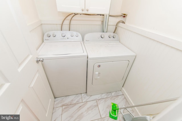 laundry room with washer and dryer, marble finish floor, cabinet space, and a wainscoted wall