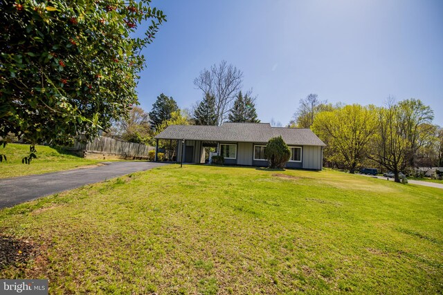 single story home featuring aphalt driveway, a carport, fence, and a front lawn