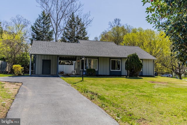 ranch-style house featuring a front yard, a carport, driveway, and board and batten siding