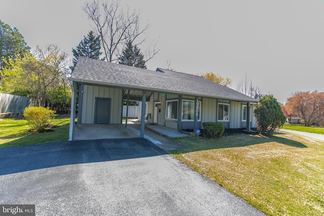 single story home with board and batten siding, a front yard, and driveway