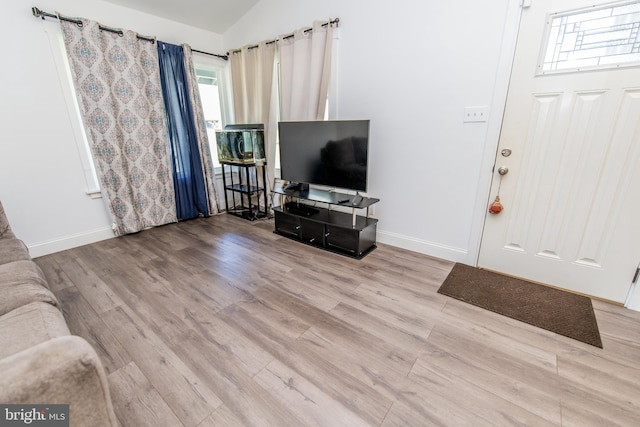 living area with baseboards, wood finished floors, and lofted ceiling