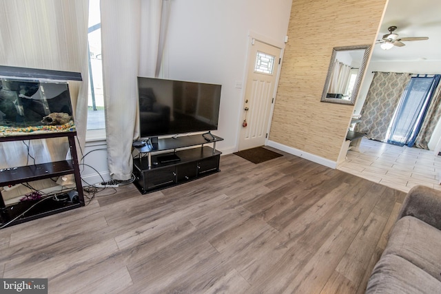 living area featuring wallpapered walls, baseboards, a ceiling fan, and wood finished floors