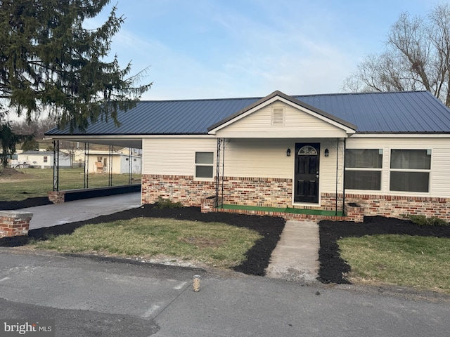 view of front of property with driveway, a front lawn, metal roof, an attached carport, and brick siding