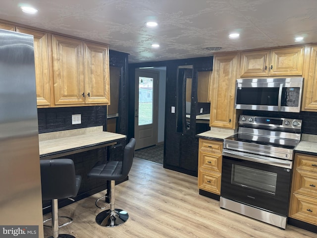 kitchen with decorative backsplash, light wood-style floors, appliances with stainless steel finishes, and light countertops