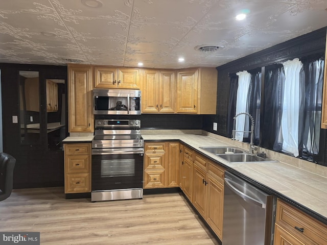 kitchen with light wood finished floors, visible vents, light countertops, stainless steel appliances, and a sink