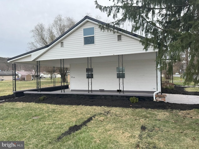 back of property with a yard and covered porch