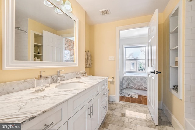 ensuite bathroom with connected bathroom, vanity, marble finish floor, baseboards, and visible vents