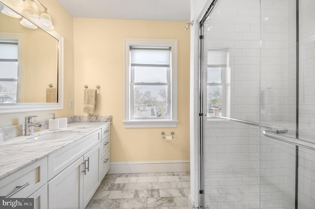 full bath with marble finish floor, vanity, baseboards, and a shower stall