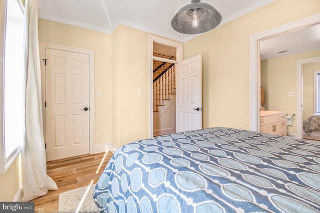 bedroom with crown molding, baseboards, visible vents, a closet, and wood finished floors