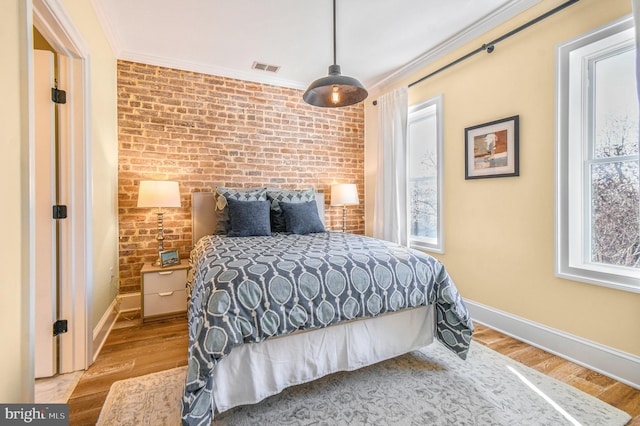 bedroom featuring ornamental molding, visible vents, multiple windows, and wood finished floors