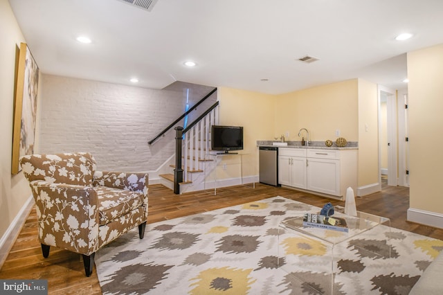 living area featuring visible vents, indoor wet bar, stairs, and wood finished floors
