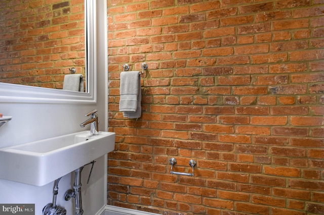 bathroom featuring a sink and brick wall