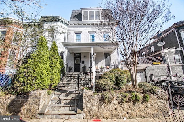 victorian home with brick siding, a porch, mansard roof, and stairs
