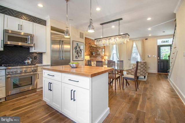 kitchen with high end appliances, butcher block countertops, visible vents, and wood finished floors
