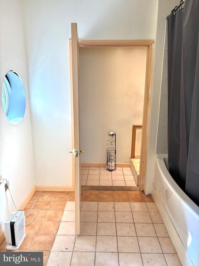 bathroom featuring baseboards, shower / bath combo with shower curtain, and tile patterned flooring