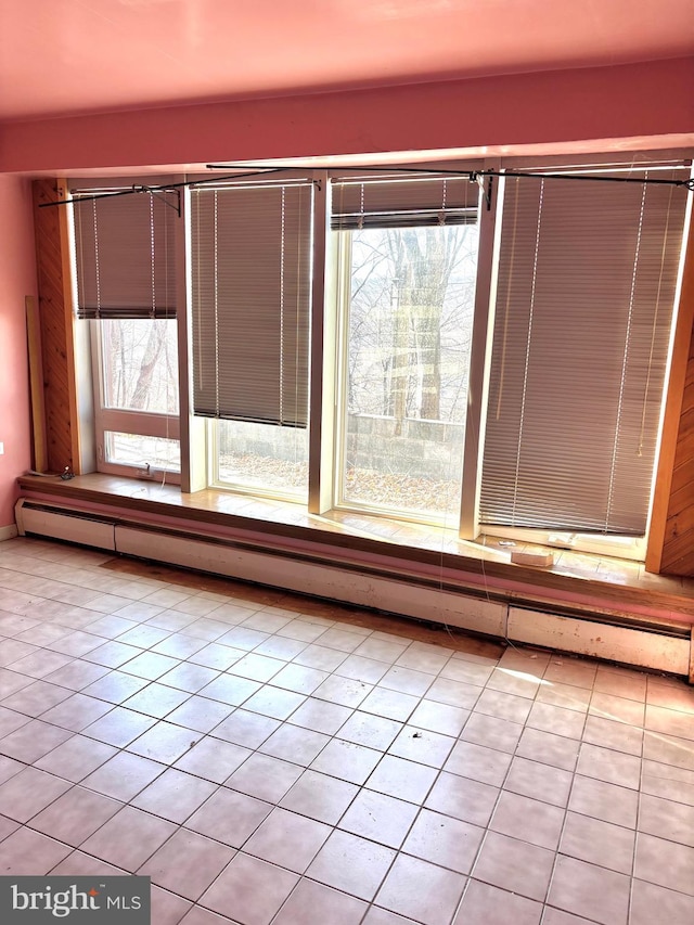 empty room with light tile patterned flooring and a baseboard heating unit