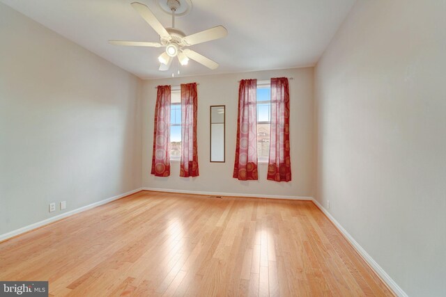 unfurnished room with a ceiling fan, light wood-type flooring, and baseboards