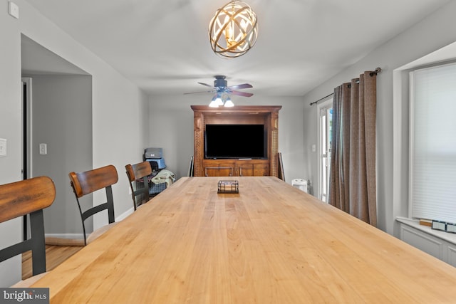 dining area with baseboards, wood finished floors, and ceiling fan with notable chandelier