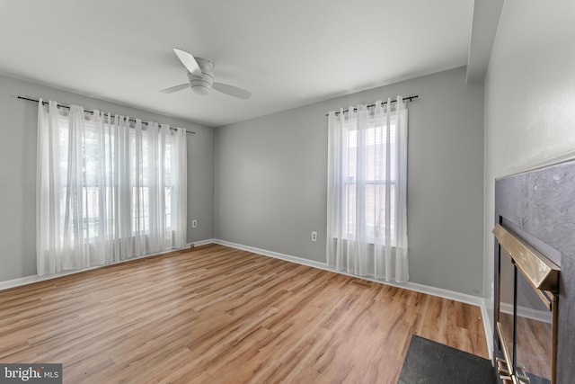 unfurnished living room featuring baseboards, a ceiling fan, and wood finished floors
