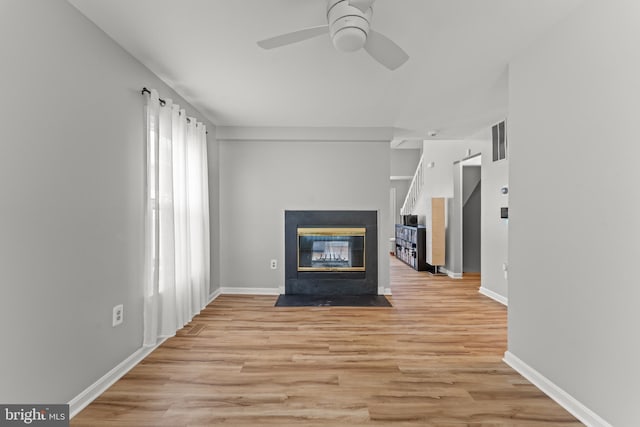 unfurnished living room featuring ceiling fan, light wood finished floors, a multi sided fireplace, and visible vents