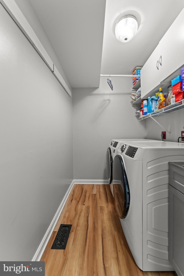 clothes washing area with independent washer and dryer, baseboards, visible vents, and light wood-style floors