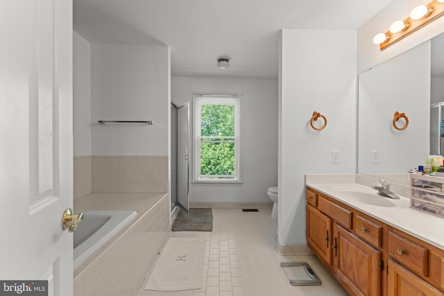 bathroom with toilet, vanity, tile patterned flooring, a relaxing tiled tub, and baseboards