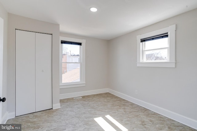 unfurnished bedroom with multiple windows, baseboards, and a closet