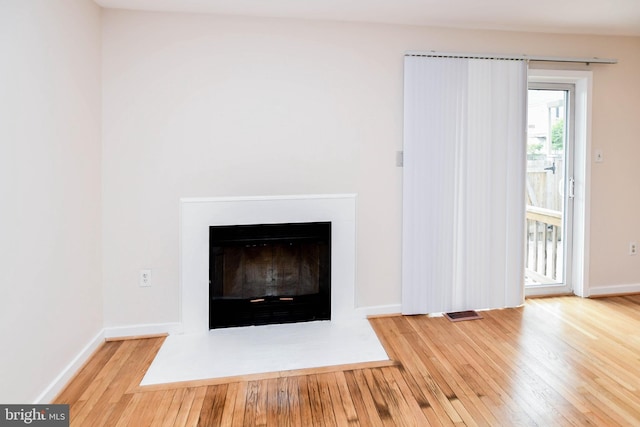 room details with baseboards, a fireplace with flush hearth, and wood finished floors