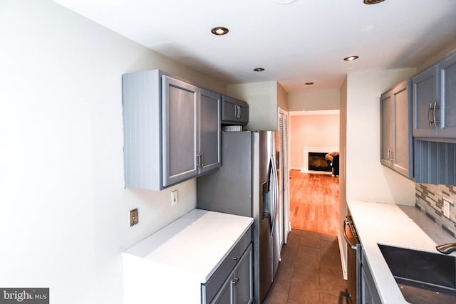 kitchen featuring stainless steel fridge, a sink, decorative backsplash, and light countertops
