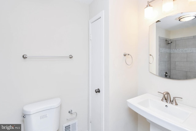 full bath with a sink, toilet, a shower, and visible vents