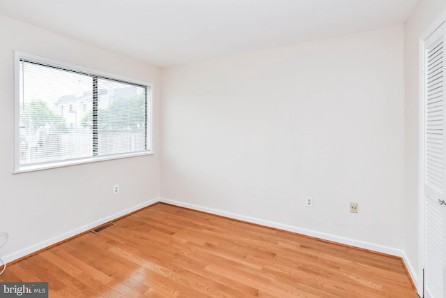 unfurnished bedroom with baseboards, a closet, light wood-style flooring, and visible vents