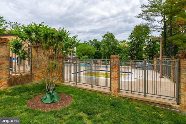 view of gate with fence and a community pool