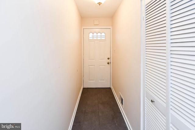 doorway featuring dark tile patterned flooring, baseboards, and visible vents