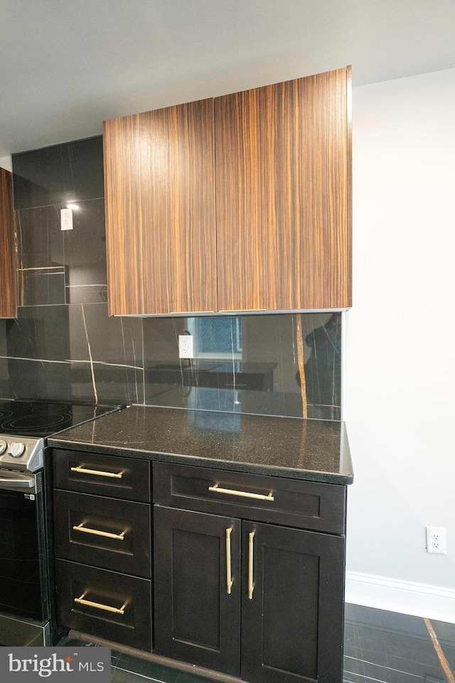 2005 N Lawrence St, Philadelphia, PA 19122 - kitchen featuring electric stove, decorative backsplash, dark stone countertops, baseboards, and dark cabinetry