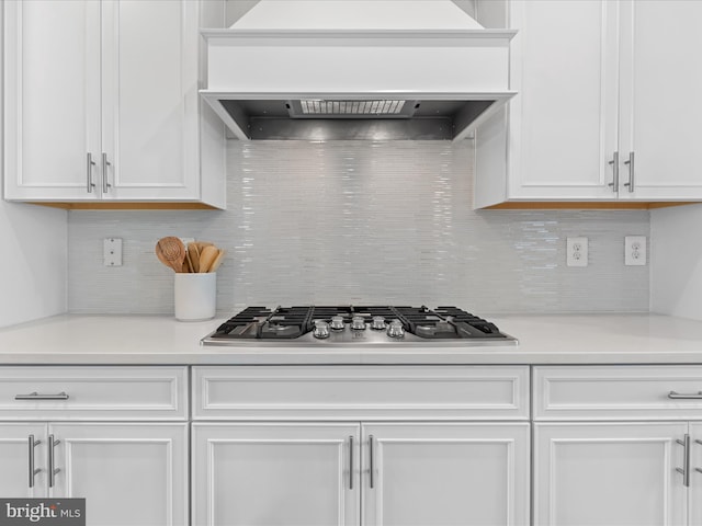 24239 Canoe Dr Unit 204, Millsboro, DE 19966 - kitchen featuring custom exhaust hood, stainless steel gas cooktop, white cabinetry, and backsplash