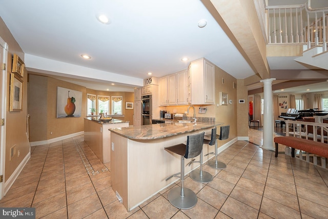 kitchen featuring light tile patterned flooring, a peninsula, decorative columns, and recessed lighting