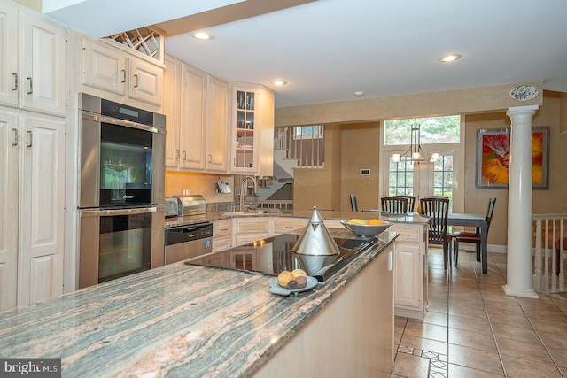 kitchen with light stone counters, glass insert cabinets, light tile patterned flooring, stainless steel appliances, and a sink
