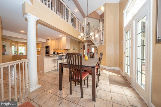 dining space with light tile patterned floors, baseboards, an inviting chandelier, and a towering ceiling