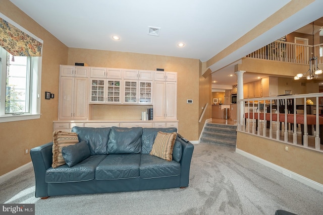 living area featuring carpet, ornate columns, recessed lighting, baseboards, and a notable chandelier