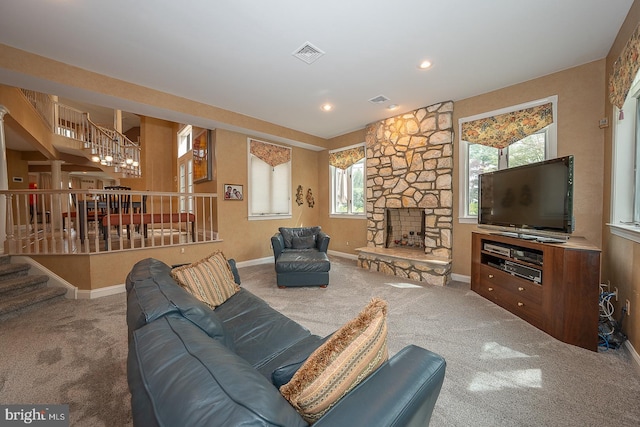 carpeted living area featuring visible vents, a stone fireplace, stairway, and baseboards