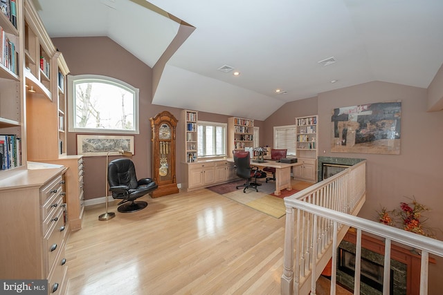 home office featuring visible vents, light wood-style flooring, and lofted ceiling