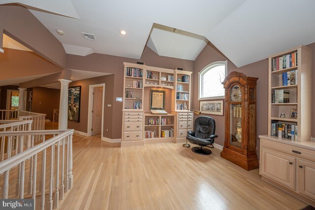 living area with light wood-style flooring, decorative columns, vaulted ceiling, and visible vents