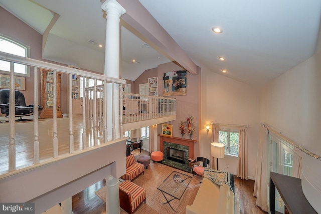 living area featuring decorative columns, a high end fireplace, beamed ceiling, recessed lighting, and high vaulted ceiling