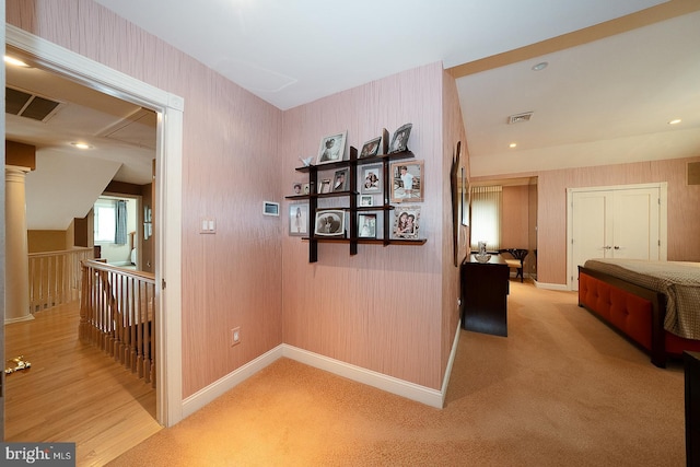 hall with an upstairs landing, visible vents, baseboards, and wallpapered walls