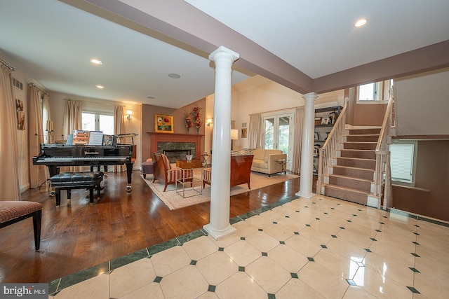 living area featuring recessed lighting, ornate columns, a high end fireplace, and a healthy amount of sunlight