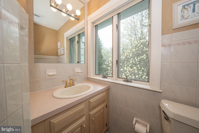bathroom with vanity, visible vents, tile walls, and toilet
