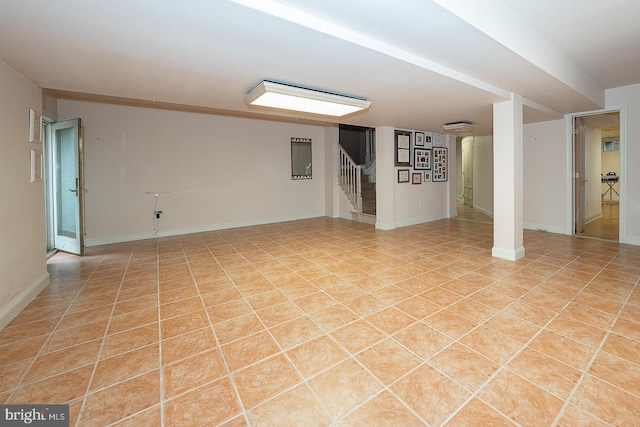 unfurnished room featuring light tile patterned floors, baseboards, and stairway